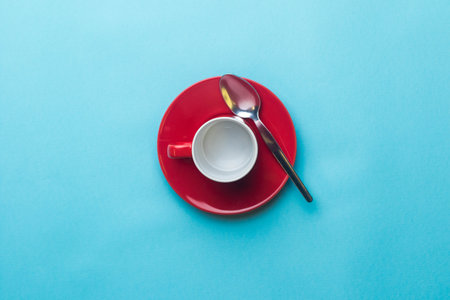 An Espresso coffee cup, spoon and saucer on a blue backgroundの写真素材