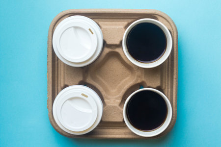 Two open and two with lids cups of black coffee on a cardboard trayの写真素材