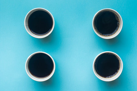 4 open cups of black coffee on a blue black groundの写真素材