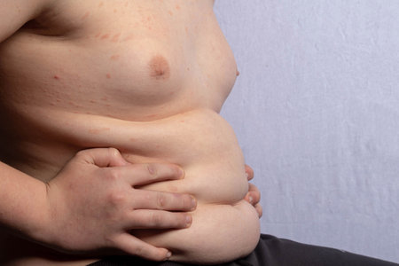 An overweight shirtless caucasian teenage boy sitting downの写真素材