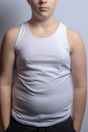 An overweight shirtless caucasian teenage boy wearing a sleevless top