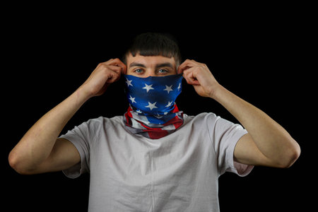 Teenage boy wearing an American flag mask against a black backgroundの写真素材