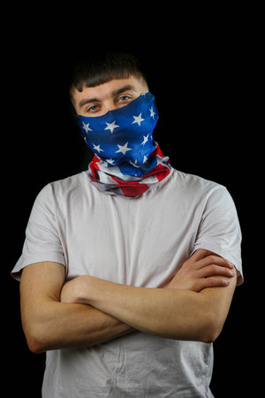 Teenage boy wearing an American flag mask against a black backgroundの写真素材