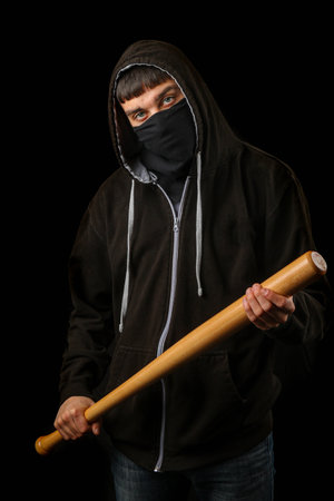 Teenage boy with a black mask a hoodie and a  baseball batの写真素材