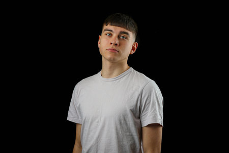 A portrait of a teenage boy against a black background