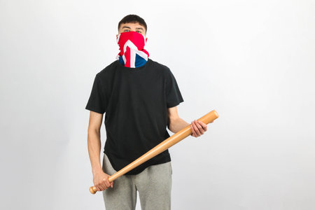 Teenage boy wearing an Union Jack mask holding  a baseball bat against a white backgroundの写真素材