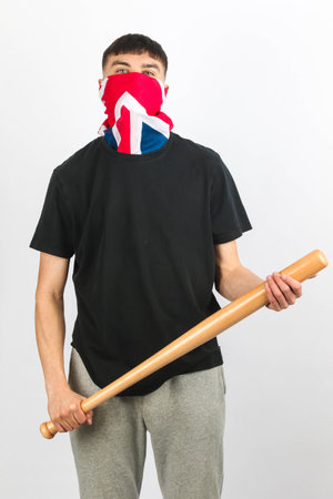 Teenage boy wearing an Union Jack mask holding  a baseball bat against a white background