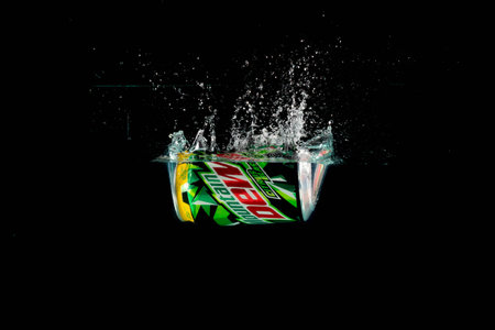 London, United Kingdom, 24th July 2023: A Can of Mountain Dew splashing into water against a black...