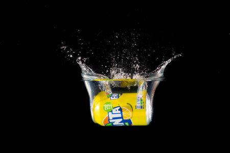 London, United Kingdom, 24th July 2023: A Can of Lemon Fanta splashing into water against a black backgroundのeditorial素材