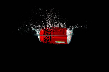 London, United Kingdom, 24th July 2023: A Can of Coke Zero splashing into water against a black...