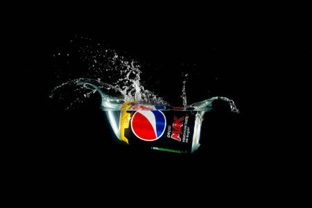 London, United Kingdom, 24th July 2023: A Can of Pepsi Max splashing into water against a black...