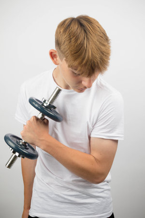 Portrait of a 14 year old caucasian teenage boy using a dumbbellの写真素材
