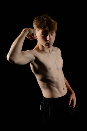 Portrait of a sporty shirtless teenage boy flexing his musclesの写真素材