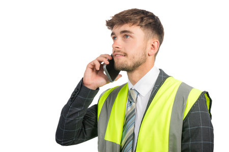 Portrait of a happy business man in a suit, with a hi-vis vest using a mobile phoneの写真素材