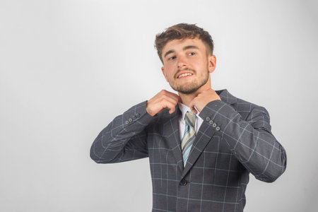 Portrait of a young entrepreneur in a suit and tie adjsuting his collar against a plain backgroundの写真素材