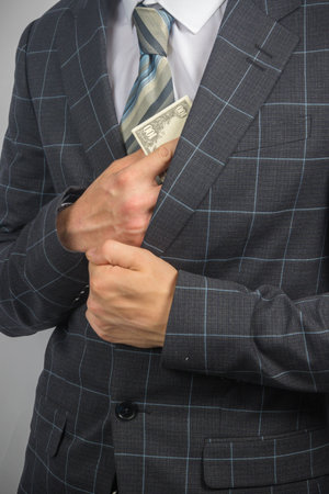 Portrait of a young entrepreneur in a suit and tie holding US Dollars