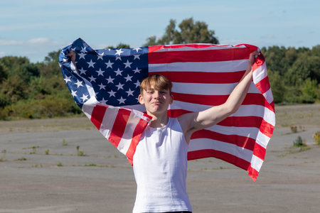 A happy and laughing teenage boy waving the American Flag