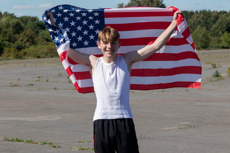 A happy and laughing teenage boy waving the American Flagの写真素材