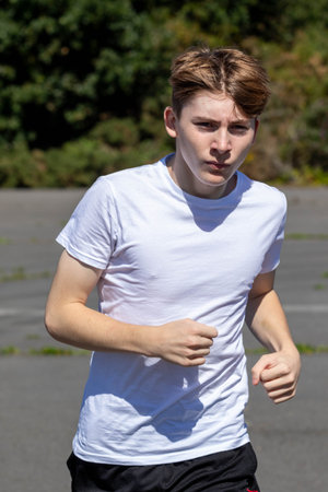 Fit and sporty teenage boy running during a warm summerâs afternoonの写真素材