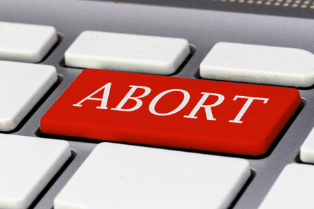 A red key on a computer keyboard reading ABORT in capital letters