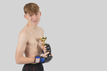 Shirtless male teenage MMA fighter with a trophyの写真素材