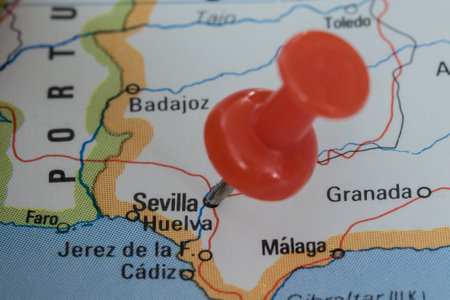 A red pin stuck into a map of Western Europe, pinpointing the location of Sevillaの写真素材
