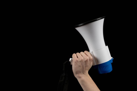 A Megaphone held in a hand isolated against a black backgroundの写真素材