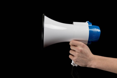 A Megaphone held in a hand isolated against a black backgroundの写真素材