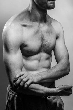 A young male body with well-defined abs and chest. Model with shirtless torso. Concept of body care, male health, fitness, youth, masculinity, health, weightloss, bodybuildingの写真素材