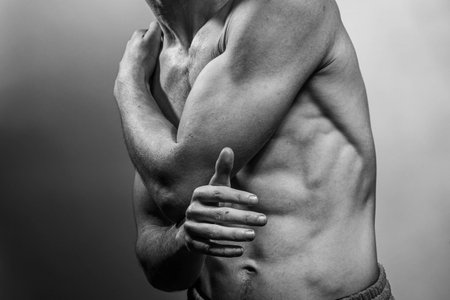 A young male body with well-defined abs and chest. Model with shirtless torso. Concept of body care, male health, fitness, youth, masculinity, health, weightloss, bodybuildingの写真素材