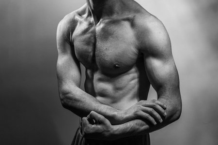 A young male body with well-defined abs and chest. Model with shirtless torso. Concept of body care, male health, fitness, youth, masculinity, health, weightloss, bodybuildingの写真素材
