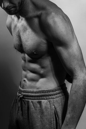 A young male body with well-defined abs and chest. Model with shirtless torso. Concept of body care,...