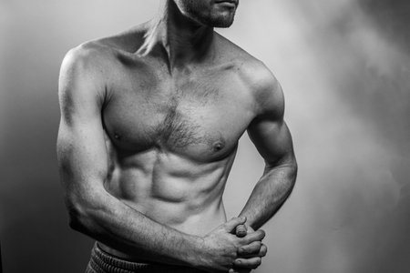 A young male body with well-defined abs and chest. Model with shirtless torso. Concept of body care, male health, fitness, youth, masculinity, health, weightloss, bodybuildingの写真素材