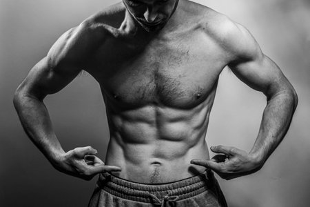 A young male body with well-defined abs and chest. Model with shirtless torso. Concept of body care, male health, fitness, youth, masculinity, health, weightloss, bodybuildingの写真素材