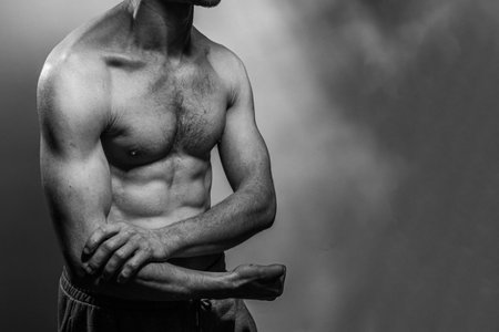 A young male body with well-defined abs and chest. Model with shirtless torso. Concept of body care, male health, fitness, youth, masculinity, health, weightloss, bodybuildingの写真素材