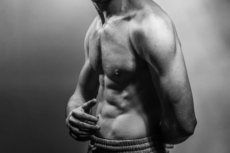 A young male body with well-defined abs and chest. Model with shirtless torso. Concept of body care, male health, fitness, youth, masculinity, health, weightloss, bodybuildingの写真素材