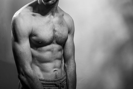 A young male body with well-defined abs and chest. Model with shirtless torso. Concept of body care, male health, fitness, youth, masculinity, health, weightloss, bodybuildingの写真素材