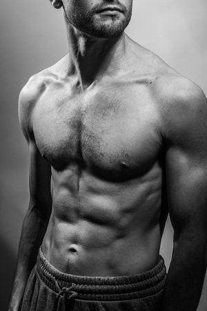 A young male body with well-defined abs and chest. Model with shirtless torso. Concept of body care, male health, fitness, youth, masculinity, health, weightloss, bodybuildingの写真素材