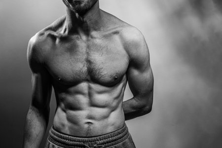 A young male body with well-defined abs and chest. Model with shirtless torso. Concept of body care, male health, fitness, youth, masculinity, health, weightloss, bodybuildingの写真素材