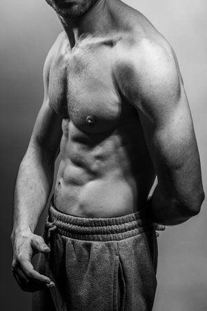 A young male body with well-defined abs and chest. Model with shirtless torso. Concept of body care, male health, fitness, youth, masculinity, health, weightloss, bodybuildingの写真素材