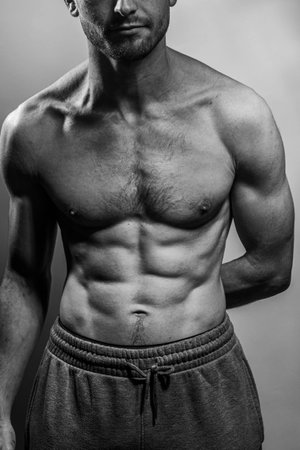 A young male body with well-defined abs and chest. Model with shirtless torso. Concept of body care, male health, fitness, youth, masculinity, health, weightloss, bodybuildingの写真素材