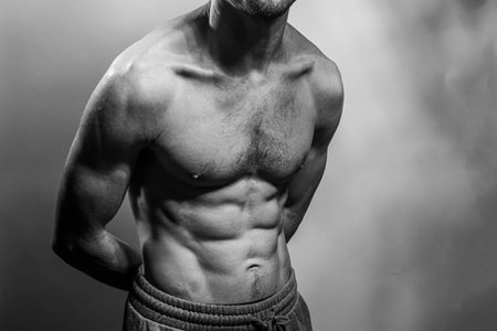 A young male body with well-defined abs and chest. Model with shirtless torso. Concept of body care, male health, fitness, youth, masculinity, health, weightloss, bodybuildingの写真素材