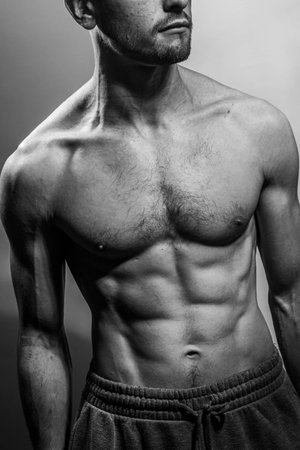 A young male body with well-defined abs and chest. Model with shirtless torso. Concept of body care, male health, fitness, youth, masculinity, health, weightloss, bodybuildingの写真素材