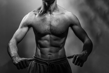 A young male body with well-defined abs and chest. Model with shirtless torso. Concept of body care, male health, fitness, youth, masculinity, health, weightloss, bodybuildingの写真素材