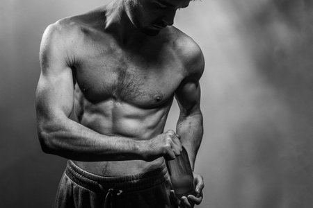 A young male body holding a water bottle, with well-defined abs and chest. Model with shirtless torso. Concept of body care, male health, fitness, youth, masculinity, health, weightloss, bodybuildingの写真素材