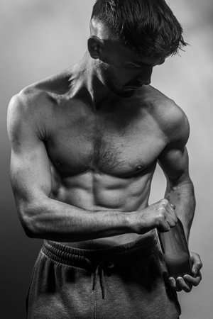 A young male body holding a water bottle, with well-defined abs and chest. Model with shirtless torso. Concept of body care, male health, fitness, youth, masculinity, health, weightloss, bodybuildingの写真素材