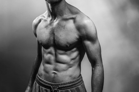 A young male body with well-defined abs and chest. Model with shirtless torso. Concept of body care, male health, fitness, youth, masculinity, health, weightloss, bodybuildingの写真素材