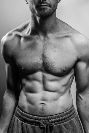 A young male body with well-defined abs and chest. Model with shirtless torso. Concept of body care, male health, fitness, youth, masculinity, health, weightloss, bodybuildingの写真素材