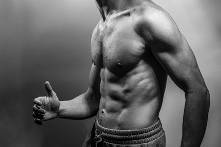 A young male body with well-defined abs and chest. Model with shirtless torso. Concept of body care, male health, fitness, youth, masculinity, health, weightloss, bodybuildingの写真素材