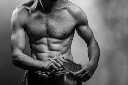 A young male body holding a water bottle, with well-defined abs and chest. Model with shirtless torso. Concept of body care, male health, fitness, youth, masculinity, health, weightloss, bodybuildingの写真素材